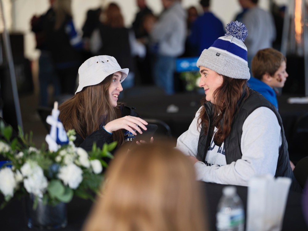 2 women looking at each other with picture in hand on phone